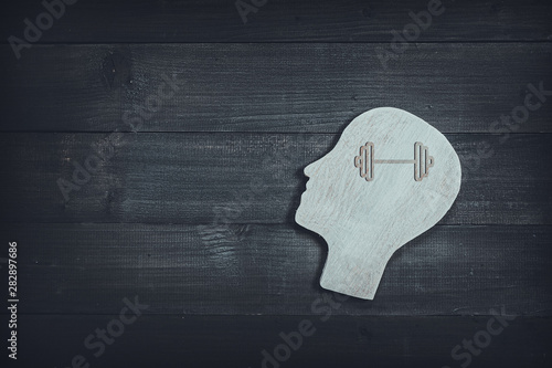 Human head and face with barbell sign on wood table background. Brain of thinking about health , Symbol of Process and Positive Mind concept