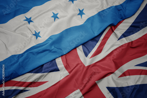 waving colorful flag of great britain and national flag of honduras.
