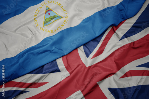 waving colorful flag of great britain and national flag of nicaragua.