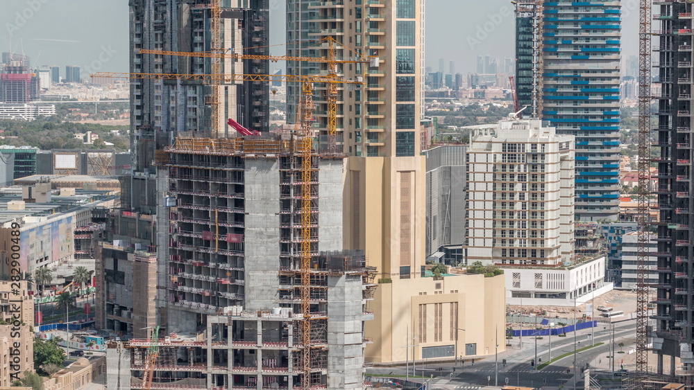 Aerial view of a skyscraper under construction with huge cranes in Dubai timelapse. United Arab Emirates