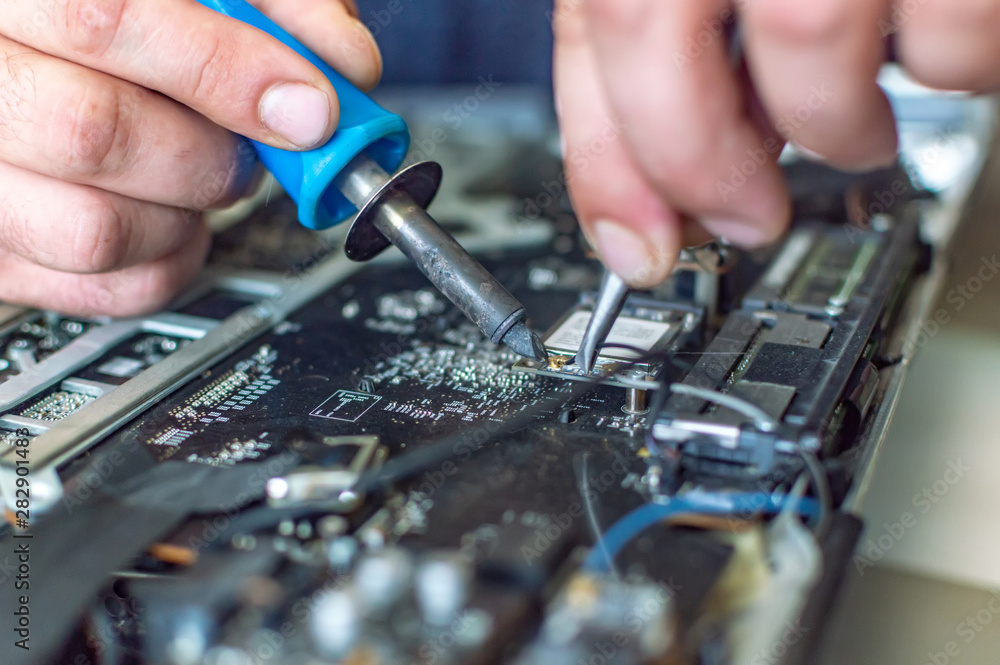 a man repairs a computer, solders a board, repairs electronics and modern technologies a man repairs a computer, solders a board, repairs electronics and modern technologies