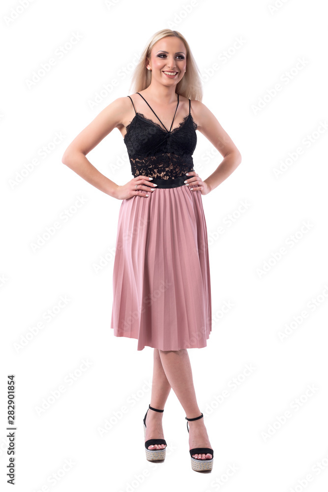 Cheerful relaxed young blonde woman in pleated skirt and lace top smiling and looking away. Full body isolated on white background. 