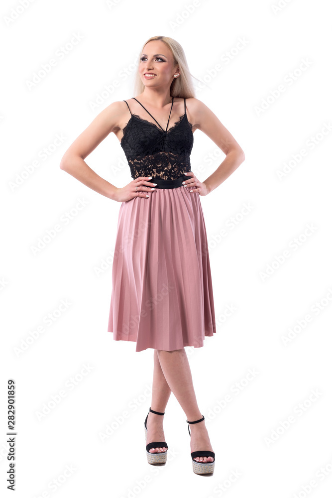 Beautiful happy blonde woman in salmon pleated long skirt and black lace top looking up. Full body isolated on white background. 