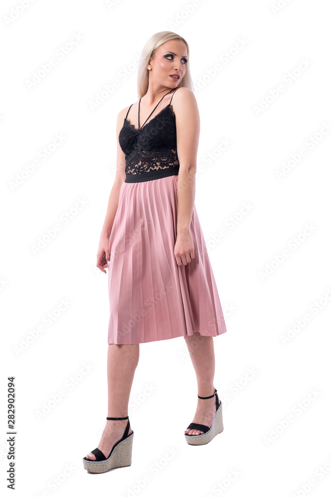 Young sexy blonde woman in summer clothes walking and looking back over shoulder. Full body isolated on white background. 