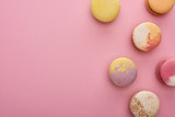 top view of multicolored delicious French macaroons on pink background