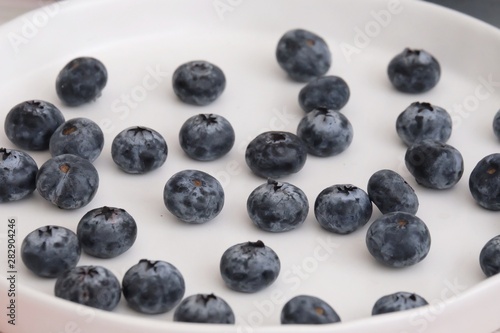 Many fresh blueberries in a white plate in a kitchen area