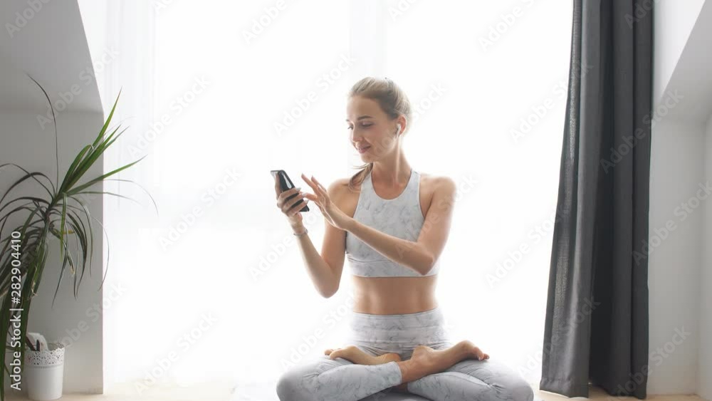 Fitness blonde woman putting on earphones getting ready for morning pilates listening to music with headphones Fitness blonde woman putting on earphones getting ready for morning pilates listening to music with headphones
