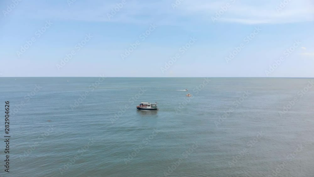 The boat sails on the sea. People sunbathe on the beach. Aerial view of beach and sea. Wave on the sea, ocean. Beach. Quadcopter. The boat sails on the sea. People sunbathe on the beach. Aerial view of beach and sea. Wave on the sea, ocean. Beach. Quadcopter.