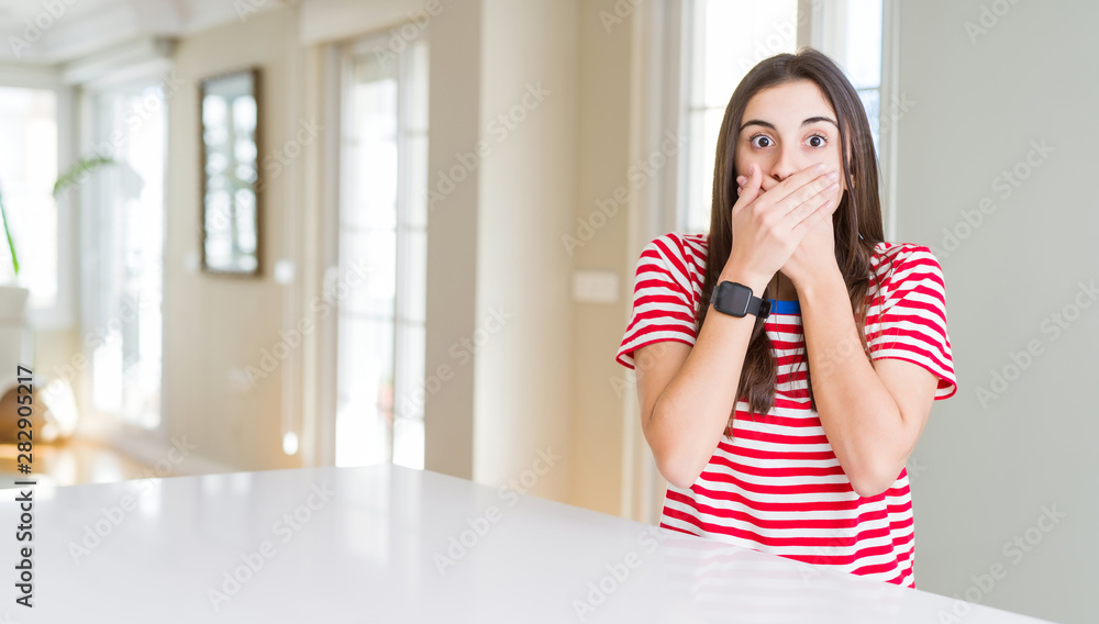 Beautiful young woman wearing casual stripes t-shirt shocked covering mouth with hands for mistake. Secret concept. Beautiful young woman wearing casual stripes t-shirt shocked covering mouth with hands for mistake. Secret concept.