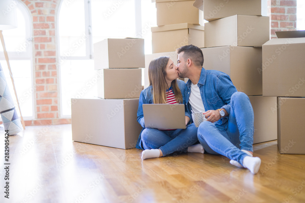 Young couple sitting on the floor around cardboard boxes using computer laptop, very happy moving to a new house Young couple sitting on the floor around cardboard boxes using computer laptop, very happy moving to a new house