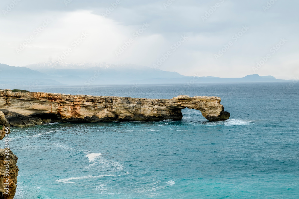 Rock in the form of a stone arch on the coast of Crete in the Mediterranean sea