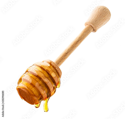 Honey drips down the wooden stick close-up on a white. Isolated.