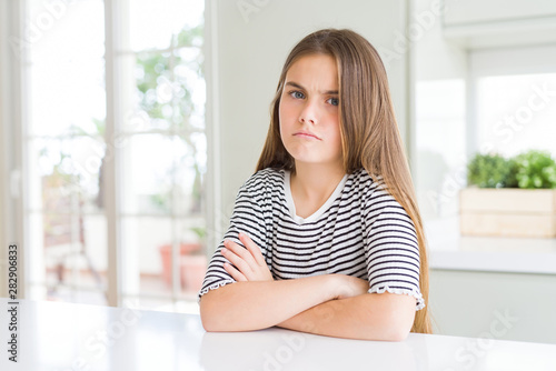 Beautiful young girl kid wearing stripes t-shirt skeptic and nervous, disapproving expression on face with crossed arms. Negative person. © Krakenimages.com