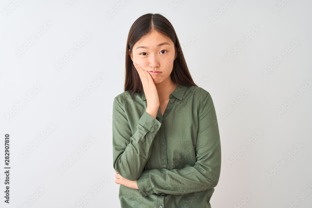 Young chinese woman wearing casual green shirt standing over isolated white background thinking looking tired and bored with depression problems with crossed arms. Young chinese woman wearing casual green shirt standing over isolated white background thinking looking tired and bored with depression problems with crossed arms.