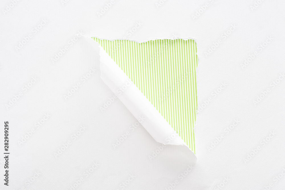 Naklejka premium white torn and rolled paper on colorful lime green striped background