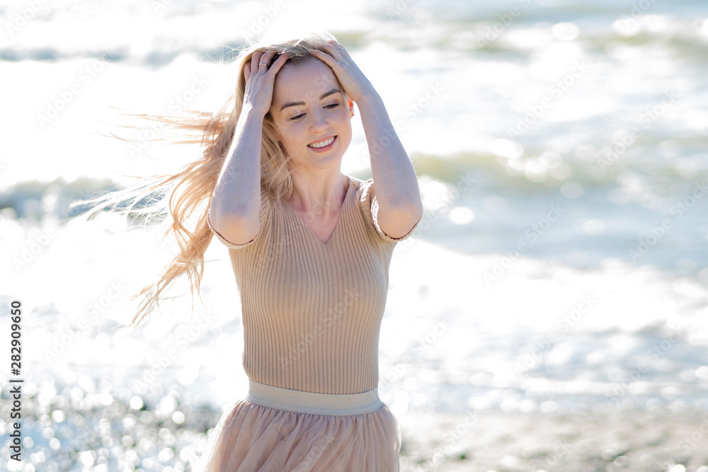Young cheerful girl on the seashore. Young blonde woman smiling.
