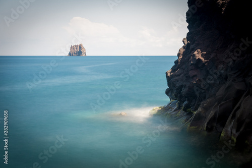 Obraz na płótnie A light house on a small island, seen from a cliff with black rock. w salonie