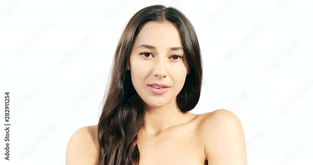 Pretty woman with dark hair touching naked shoulders and posing to camera isolated on white background, beauty and glamour