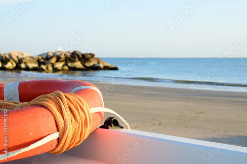 Rettungsring in der Signalfarbe Orange auf einem Rettungsboot in der Morgensonne am Meer
