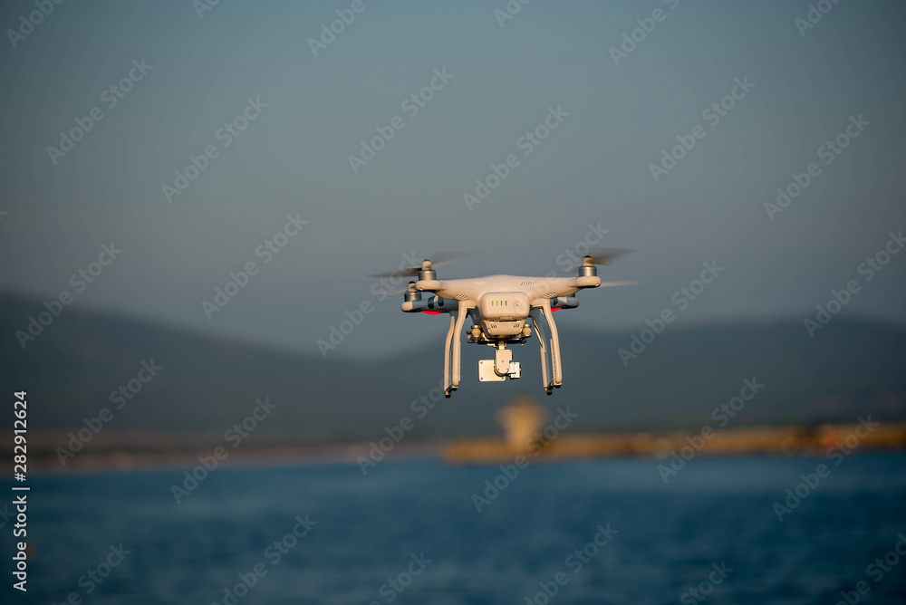 a drone with a digital camera flying over the sea a drone with a digital camera flying over the sea