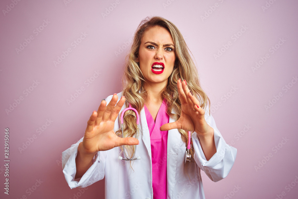 Young beautiful doctor woman using stethoscope over pink isolated background afraid and terrified with fear expression stop gesture with hands, shouting in shock. Panic concept. Young beautiful doctor woman using stethoscope over pink isolated background afraid and terrified with fear expression stop gesture with hands, shouting in shock. Panic concept.