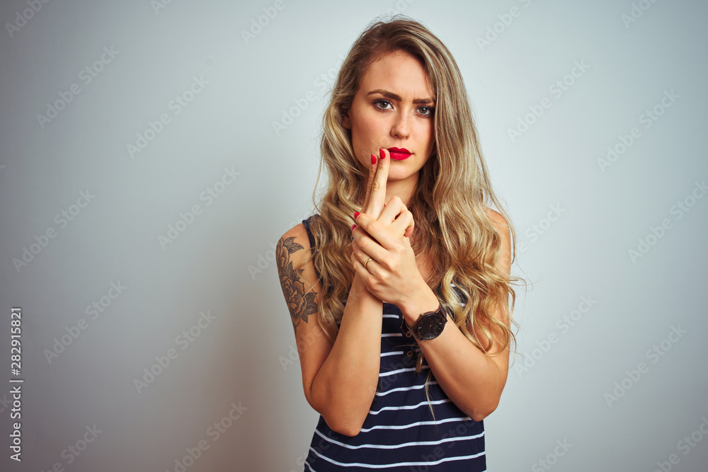 Young beautiful woman wearing stripes t-shirt standing over white isolated background Holding symbolic gun with hand gesture, playing killing shooting weapons, angry face Young beautiful woman wearing stripes t-shirt standing over white isolated background Holding symbolic gun with hand gesture, playing killing shooting weapons, angry face