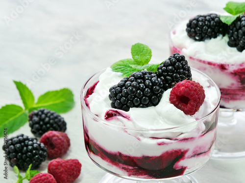 Berry fruit fool dessert in glass bowl. Sweetened and pureed blackberries folded into whipped cream topped with whole blackberries and raspberries.