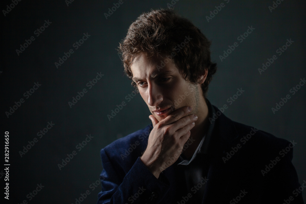 A young brunet male is holding his chin thoughtfully, pointing to the side. A young brunet male is holding his chin thoughtfully, pointing to the side.