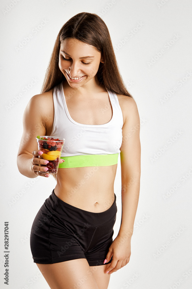 Beautiful muscular girl holding a glass of fruit Beautiful muscular girl holding a glass of fruit