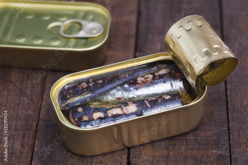 Closeup of an open can of sardines with tomato and onion on wooden table. Canned sardine.