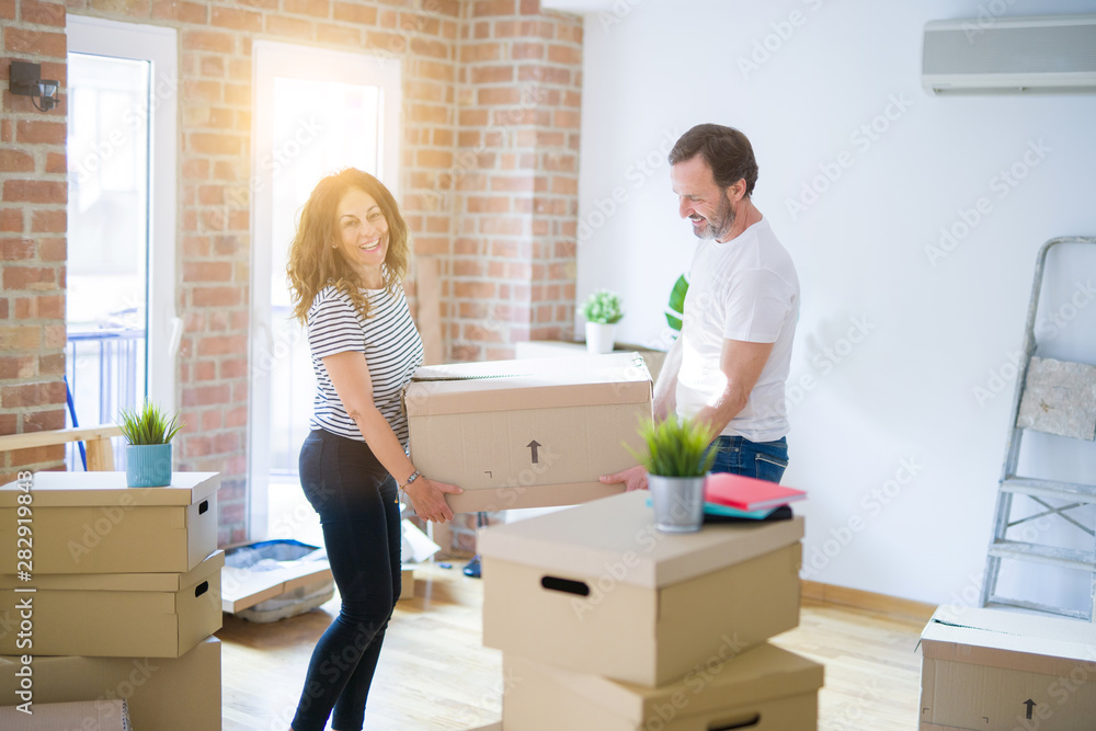 Middle age senior couple moving to a new house, holding cardboard boxing smiling happy in love with apartmant Middle age senior couple moving to a new house, holding cardboard boxing smiling happy in love with apartmant
