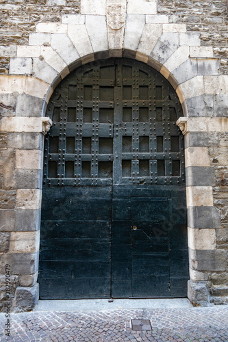 antica porta medievale in legno e ferro verde scuro con mura ad arco