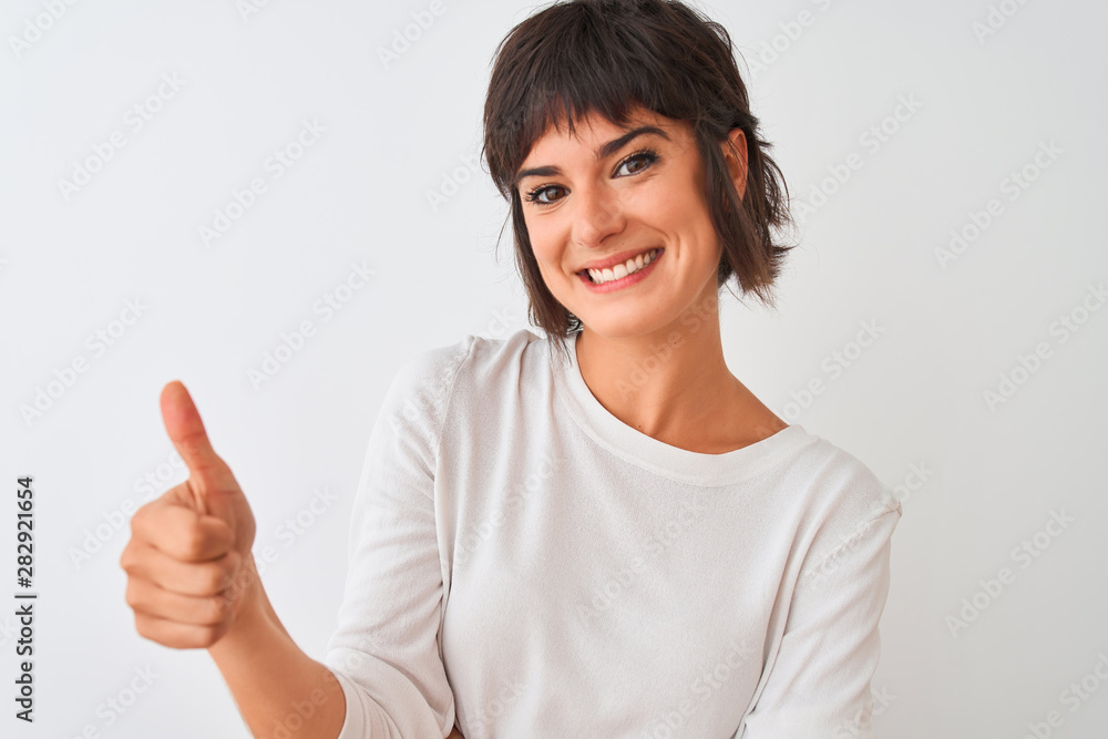 Young beautiful woman wearing casual t-shirt standing over isolated white background happy with big smile doing ok sign, thumb up with fingers, excellent sign Young beautiful woman wearing casual t-shirt standing over isolated white background happy with big smile doing ok sign, thumb up with fingers, excellent sign