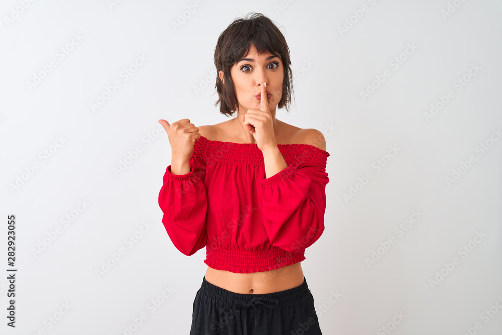 Young beautiful woman wearing red summer t-shirt standing over isolated white background asking to be quiet with finger on lips pointing with hand to the side. Silence and secret concept. Young beautiful woman wearing red summer t-shirt standing over isolated white background asking to be quiet with finger on lips pointing with hand to the side. Silence and secret concept.