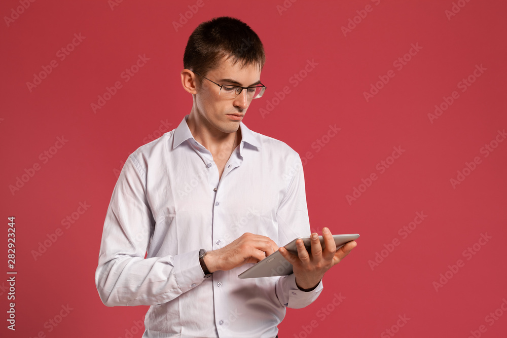 Young man in a classic white shirt is posing over a pink background. Young man in a classic white shirt is posing over a pink background.