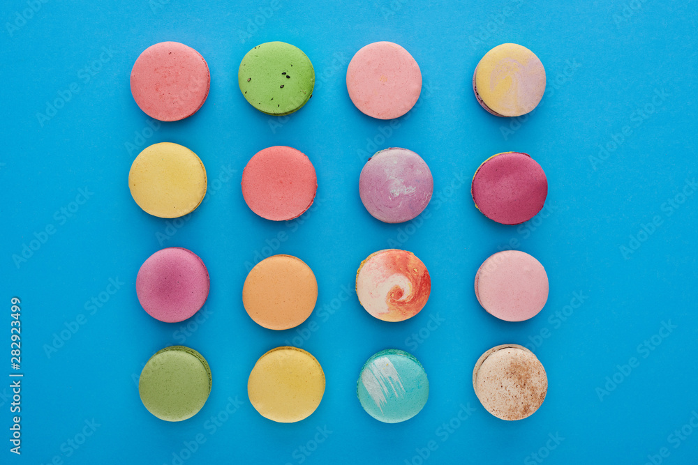 flat lay with multicolored tasty French macaroons on blue bright background flat lay with multicolored tasty French macaroons on blue bright background