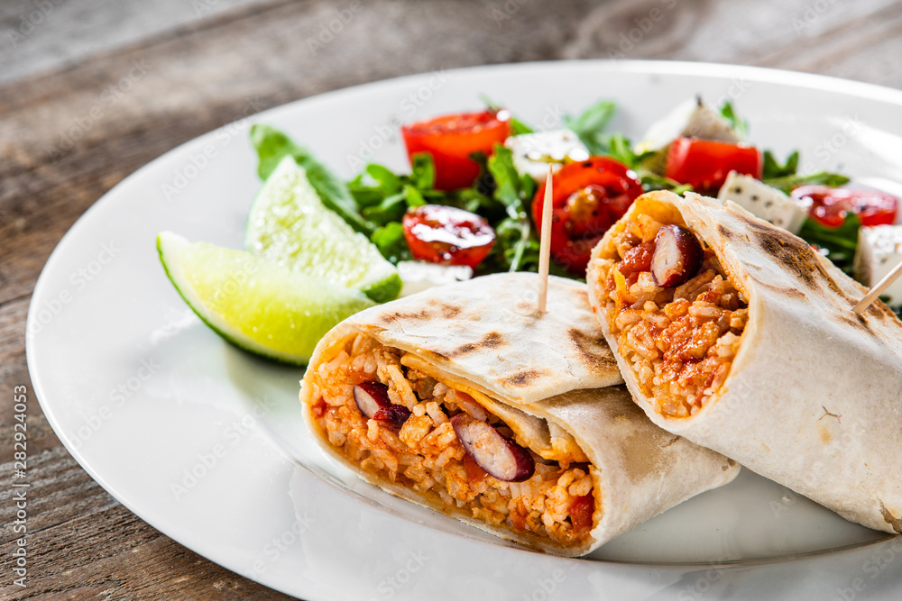Burrito with vegetable salad on white plate Burrito with vegetable salad on white plate