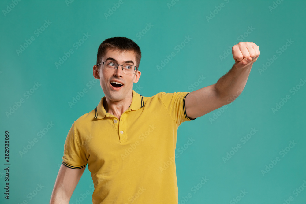 Handsome guy in a yellow casual t-shirt is posing over a blue background. Handsome guy in a yellow casual t-shirt is posing over a blue background.