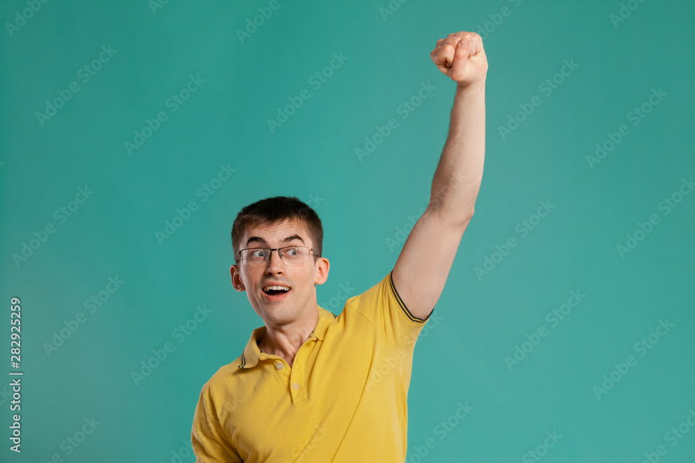 Handsome guy in a yellow casual t-shirt is posing over a blue background. Handsome guy in a yellow casual t-shirt is posing over a blue background.
