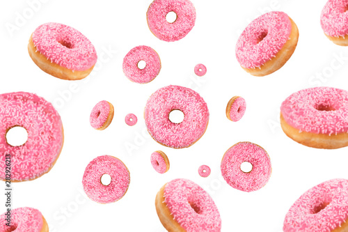 Falling or flying pink glazed doughnuts with sprinkles in motion isolated on white background. American food. Bakery and pastry products. Creative layout or pattern. Fun food concept.