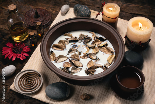 Aromatherapy concept background. Milk in a bowl with incense and essential oil on a brown wooden table background.