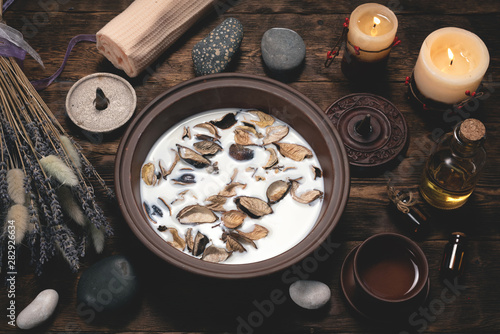 Aromatherapy concept background. Milk in a bowl with incense and essential oil on a brown wooden table background. © Dmitriy