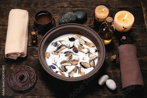 Aromatherapy concept background. Milk in a bowl with incense and essential oil on a brown wooden table background.