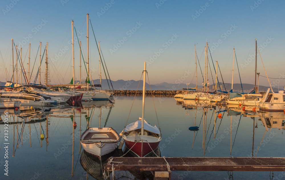 Port of Aegina town with yachts and fishermen boats docked in Aegina island, Saronic gulf, Greece, at sunrise.