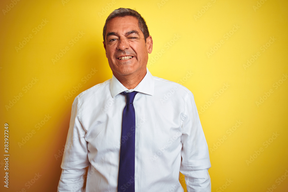 Handsome middle age businessman standing over isolated yellow background winking looking at the camera with sexy expression, cheerful and happy face. Handsome middle age businessman standing over isolated yellow background winking looking at the camera with sexy expression, cheerful and happy face.