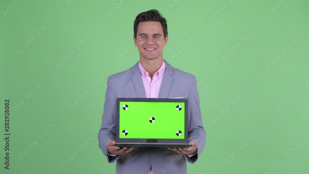 Happy young handsome businessman thinking while showing laptop Happy young handsome businessman thinking while showing laptop