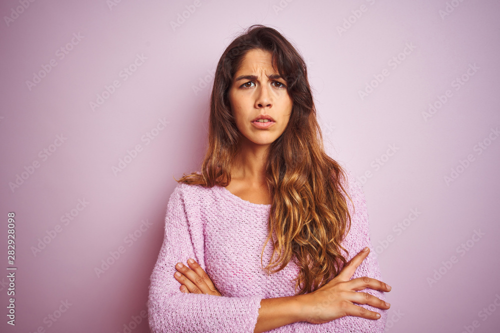 Young beautiful woman wearing sweater standing over pink isolated background skeptic and nervous, disapproving expression on face with crossed arms. Negative person. Young beautiful woman wearing sweater standing over pink isolated background skeptic and nervous, disapproving expression on face with crossed arms. Negative person.