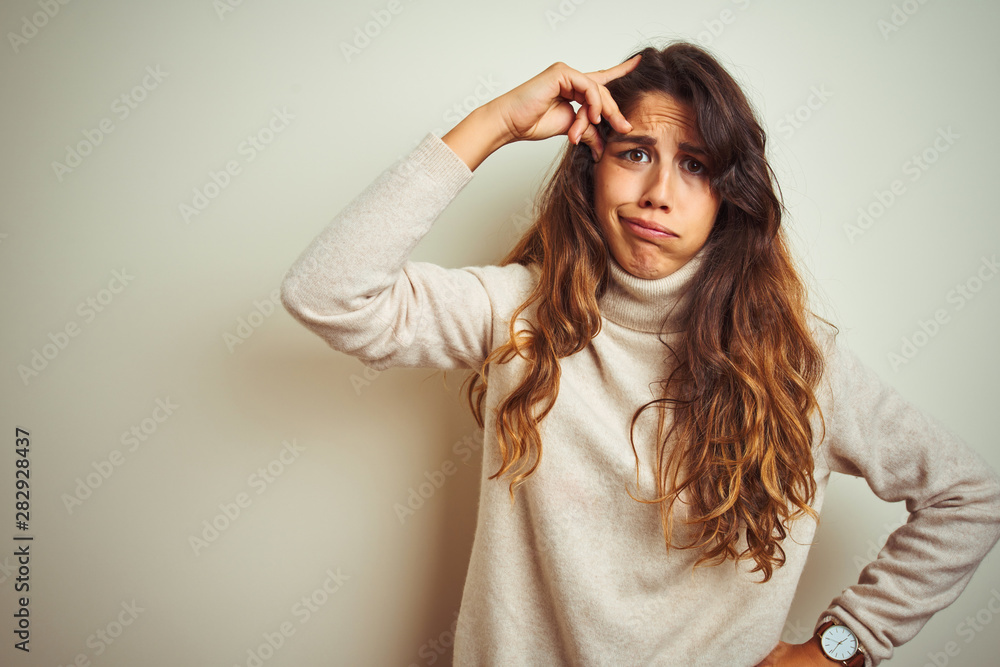 Young beautiful woman wearing winter sweater standing over white isolated background worried and stressed about a problem with hand on forehead, nervous and anxious for crisis Young beautiful woman wearing winter sweater standing over white isolated background worried and stressed about a problem with hand on forehead, nervous and anxious for crisis