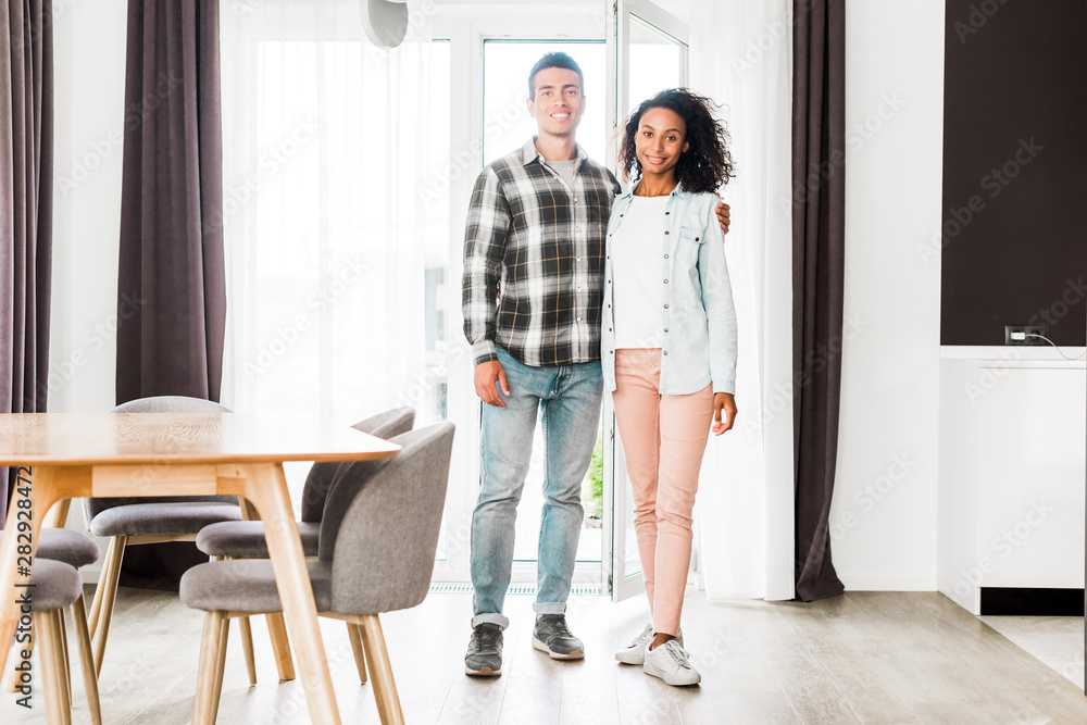 full length view of african american husband and wife hugging and looking at camera full length view of african american husband and wife hugging and looking at camera