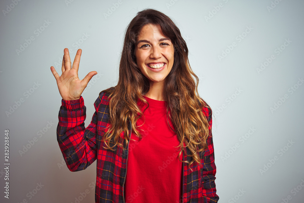 Young beautiful woman wearing red t-shirt and jacket standing over white isolated background showing and pointing up with fingers number five while smiling confident and happy. Young beautiful woman wearing red t-shirt and jacket standing over white isolated background showing and pointing up with fingers number five while smiling confident and happy.